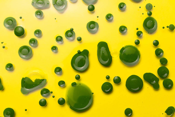 Fondo abstracto. Gotas de pintura verde en un vaso
. - Foto, imagen