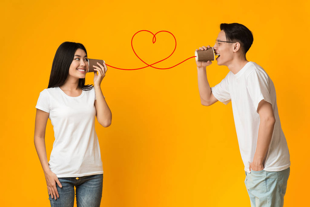 Aziatisch guy vertellen vriendin over liefde, met behulp van kan telefoon - Foto, afbeelding