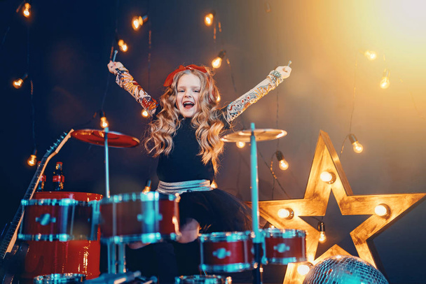 Beautiful girl playing the drums on a black background - Zdjęcie, obraz