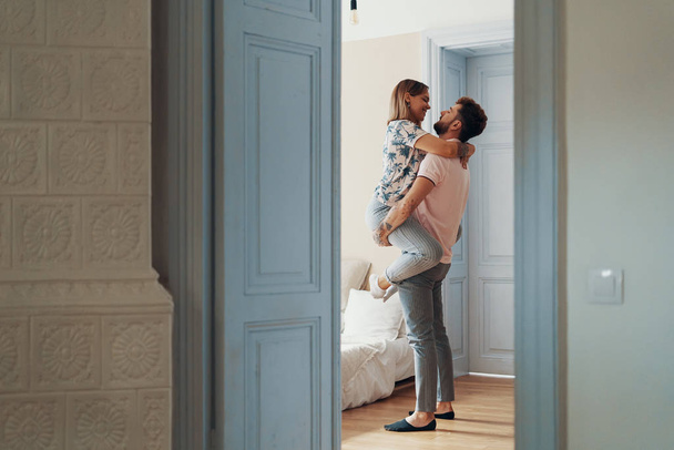 Profilbild eines liebenden jungen Paares, das sich umarmt, während es im Schlafzimmer steht - Foto, Bild