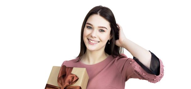 Beautiful brunette girl with a wide smile holds a gift in her hands. - Foto, Imagen