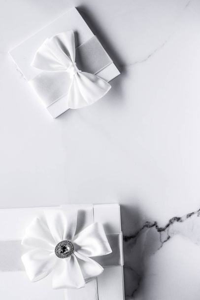 Розкішні весільні подарунки з шовковим бантом та стрічками на мармуровому фоні
 - Фото, зображення