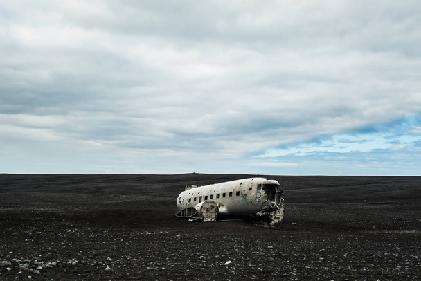 Wrecked plane on the black sand beach in Iceland. Atmospheric Icelandic landscape - Foto, Imagen