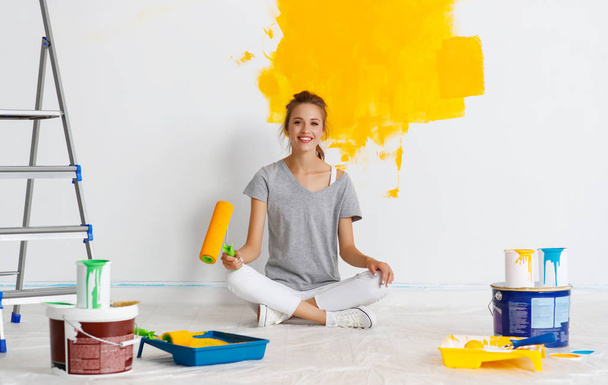 Επισκευή στο διαμέρισμα. Ευτυχισμένη νεαρή γυναίκα ζωγραφίζει τοίχους - Φωτογραφία, εικόνα