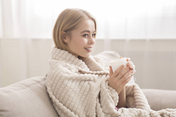 Young woman wrapped in blanket drinking hot tea - Foto, Imagem