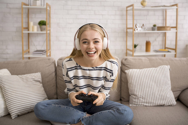 Chica feliz en auriculares inalámbricos jugando videojuego
 - Foto, imagen