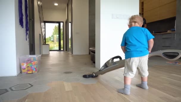 2 years old boy pushing big vacuum cleaner hoover on floor - 映像、動画