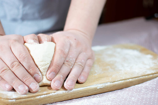 Knead the dough on a wooden board - Фото, изображение