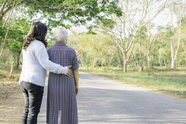 Βοήθεια και φροντίδα της Ασίας ανώτερος ή ηλικιωμένη ηλικιωμένη γυναίκα με ισχυρή υγεία, ενώ το περπάτημα στο πάρκο σε χαρούμενες φρέσκες διακοπές.  - Φωτογραφία, εικόνα