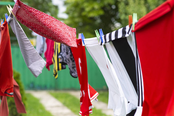 Πολύχρωμα ρούχα κρέμονται για να στεγνώσει σε μια γραμμή πλυντηρίου - Φωτογραφία, εικόνα