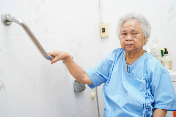 Azjatycki starszy lub starszy pani pacjentka używać toalety łazienka uchwyt bezpieczeństwa w szpitalu pielęgniarskim oddział: zdrowe silne pojęcie medyczne.  - Zdjęcie, obraz