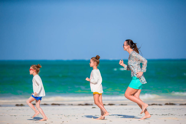 Adorable little girls and young mother on white beach - Foto, immagini