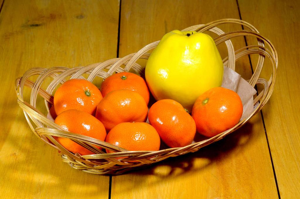 We zien een mand gevuld met mandarijnen, waaronder quince - Foto, afbeelding