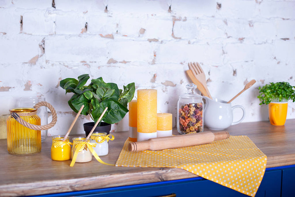 various kitchen utensils on a wooden table. concept of home decor kitchen. Kitchen tools, candles and wooden rolling pin against white brick wall. Jar with colorful pasta. Spring kitchen decor. Easter - Photo, image