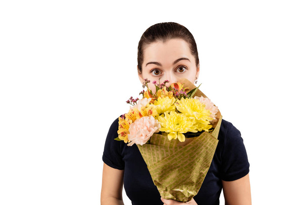 Una joven inteligente con ojos marrones y una camiseta azul sonríe con un ramo de crisantemos y flores de claveles
 - Foto, imagen