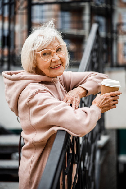 Happy aged woman with cup of coffee outdoors stock photo - Φωτογραφία, εικόνα