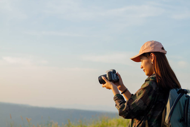 women asian with backpack taking a photo on view at sunrise seas - 写真・画像