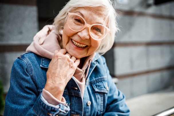 Smiling aged woman in jeans jacket stock photo - Zdjęcie, obraz
