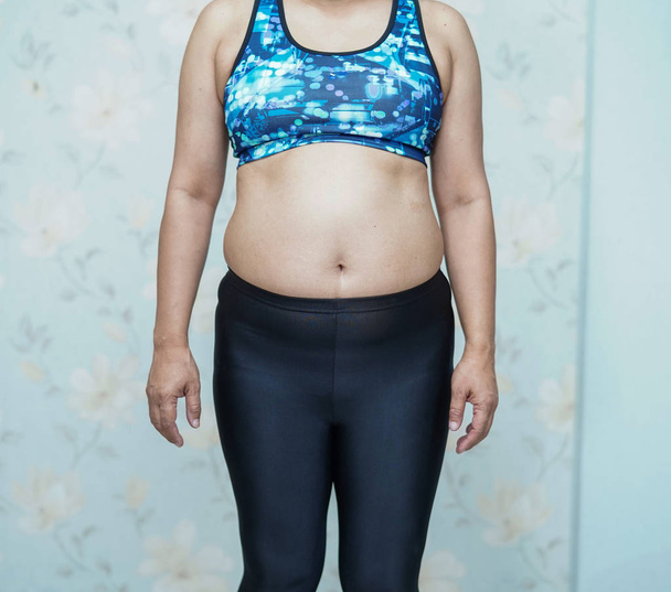 overgewicht aziatische vrouw tonen vet buik op kantoor. - Foto, afbeelding