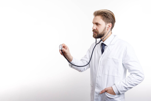Medico pensoso mezzo girato in cappotto bianco Auscultating
 - Foto, immagini