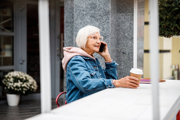 Happy aged female talking on phone in cafe stock photo - Fotoğraf, Görsel