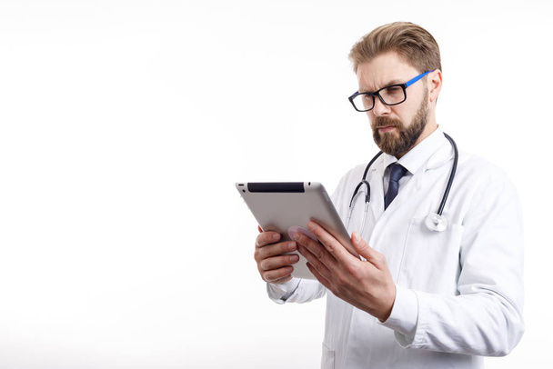 Вдумчивый доктор с бородой проверяет информацию через планшет
 - Фото, изображение