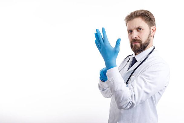 Médico de confianza en bata blanca que se pone guantes médicos azules
 - Foto, Imagen