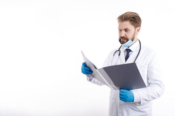 Médecin barbu en gommage blanc explorant la documentation médicale
 - Photo, image