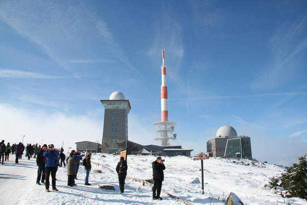 The view on the Brocken in the Harz mountains with clouds, snow, blue sky and fog - Photo, Image