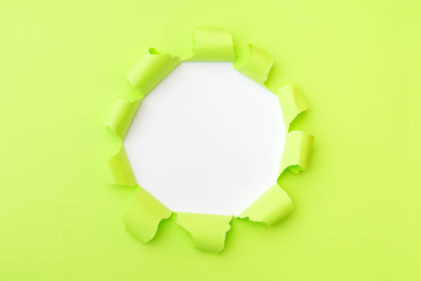 Light green paper with ripped hole in the middle background - Фото, изображение