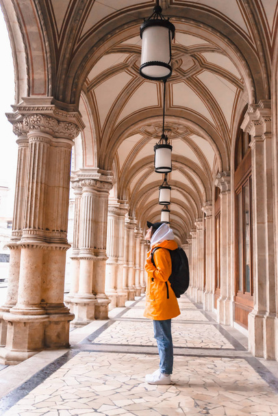 donna turista a piedi con zaino in impermeabile giallo turismo urbano
 - Foto, immagini