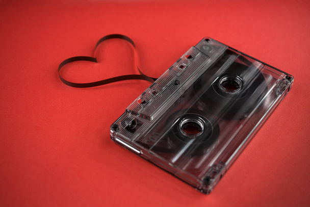 vintage old film music cassette on a trendy pink red background with film heart shaped, background music, music lovers - 写真・画像
