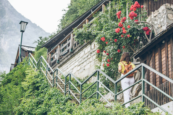young pretty tourist woman walking by small hallstatt street stairs - Photo, Image