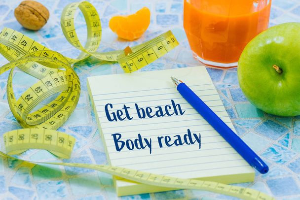 meter to measure waist size, healthy, diet food.  Notebook with the motivational slogan "Get beach-body ready". The concept of spring slimming diet, lifestyle changes. - Photo, Image
