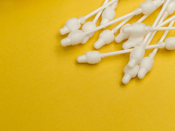 cotton buds close-up on a light yellow background, for children, hygiene and ear cleaning, cotton swab - 写真・画像
