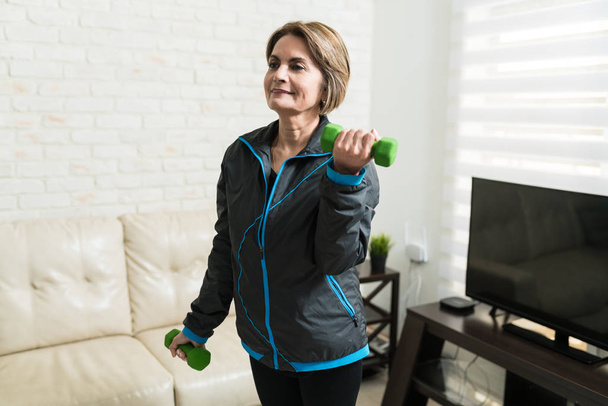 Femme âgée confiante faisant de l'exercice avec haltères à la maison
 - Photo, image