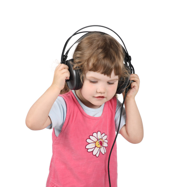 Little girl listens to music in big headphones and looks down is - Valokuva, kuva