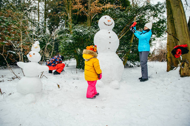 Nuori lumiukko lumipuistossa. pieni lapsi tyttö auttaa
 - Valokuva, kuva