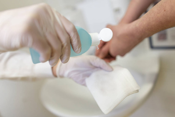 Nurse disinfects a patients hand at a sink - Photo, image
