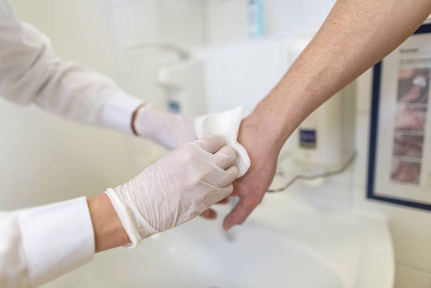Nurse disinfects a patients hand at a sink - Photo, Image