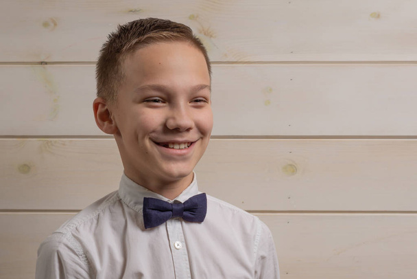 Ein Junge von 10 Jahren lächelt auf dem Hintergrund eines hölzernen W - Foto, Bild