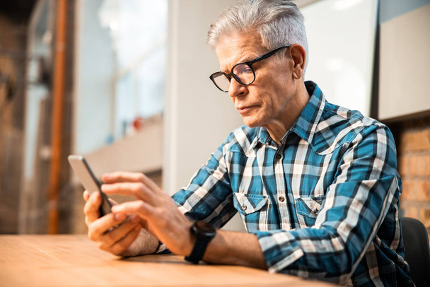 Adult man sitting at workplace with smartphone - Фото, зображення