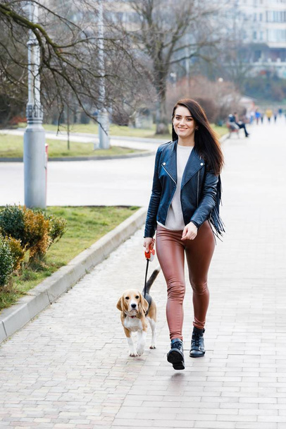 Young pretty girl walking her cute dog in the park. The girl actively spends her leisure - Fotografie, Obrázek
