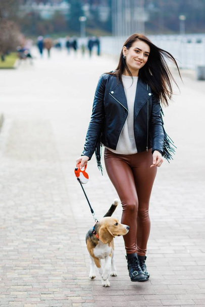 Young pretty girl walking her cute dog in the park. The girl actively spends her leisure - Photo, Image