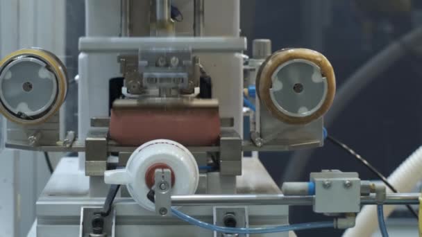Egy robot a gyárban alkalmazza a márkanevet a műanyag üvegekre párnás nyomtatással.. - Felvétel, videó