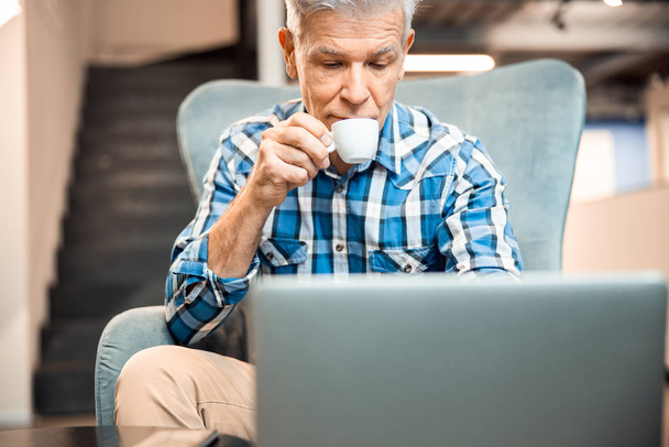 Mature man is drinking coffee in cafe - Foto, afbeelding