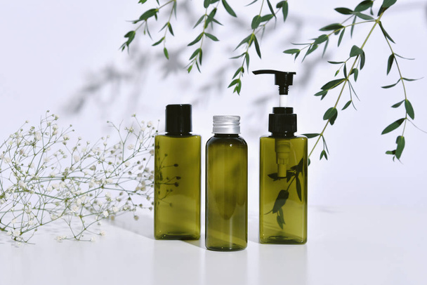 Kosmetik-Flaschenverpackung mit grünen Kräuterblättern in Schatten und Lichteffekt, Leeretikett für Bio-Branding-Mock-up, natürliches Kosmetik-Produktkonzept. - Foto, Bild