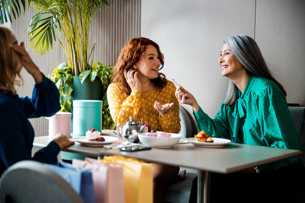 Female friends chatting and laughing in cafe - Photo, image