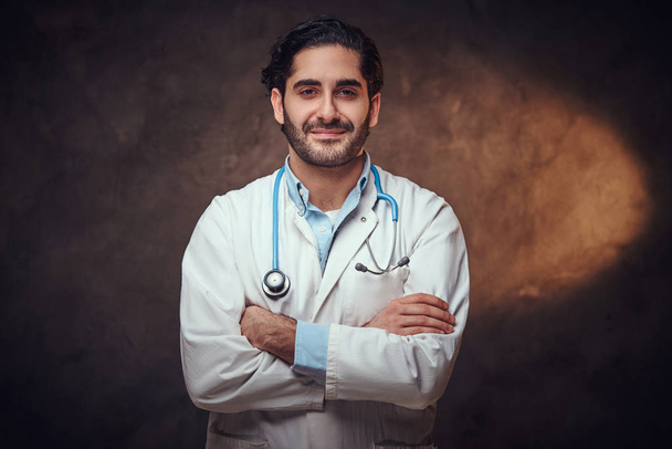 Portrait of smart handsome doctor over dark background. - Photo, Image