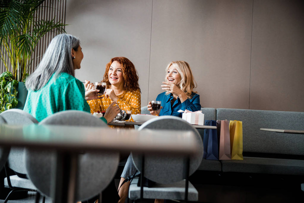 Cheerful female friends drinking tea and chatting in cafe - Fotoğraf, Görsel